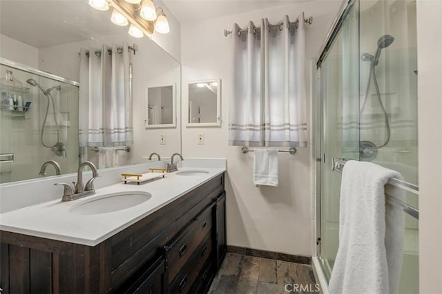 full bath with baseboards, a sink, and a shower stall