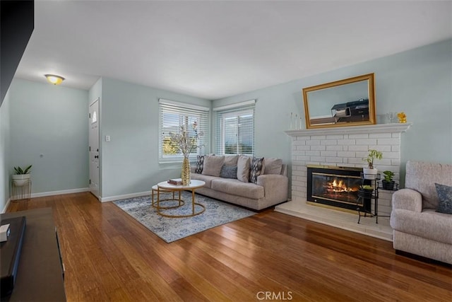 living room with a fireplace, baseboards, and wood finished floors