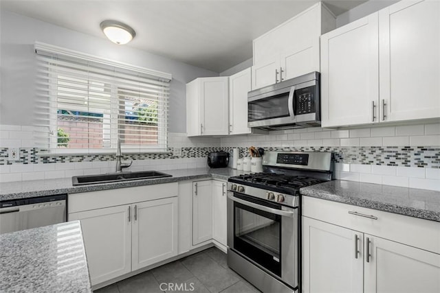 kitchen with appliances with stainless steel finishes, a sink, white cabinetry, and decorative backsplash