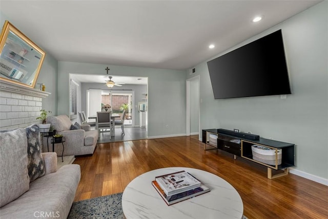 living room with recessed lighting, visible vents, baseboards, and wood finished floors