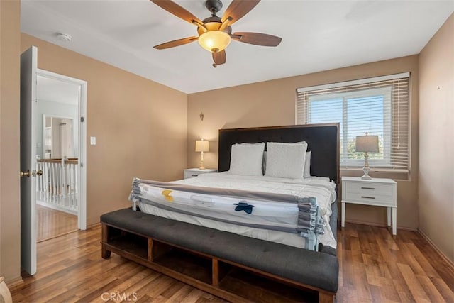 bedroom featuring ceiling fan, baseboards, and wood finished floors