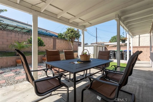 view of patio / terrace with a storage shed, a fenced backyard, outdoor dining area, and an outdoor structure