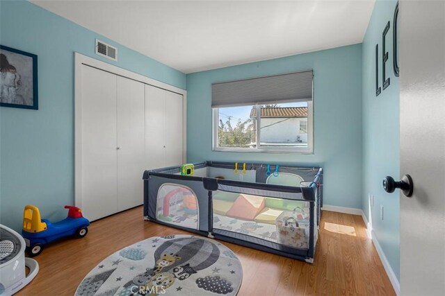 bedroom with baseboards, a closet, visible vents, and wood finished floors