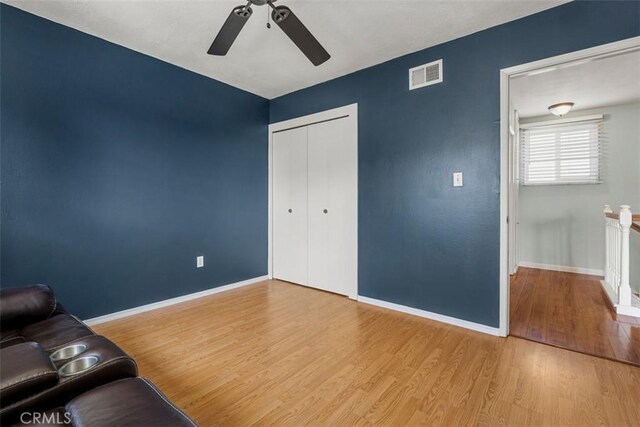 interior space with a ceiling fan, visible vents, baseboards, and wood finished floors