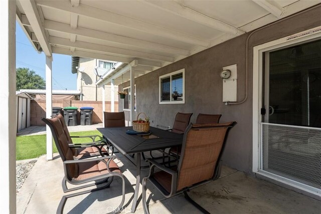 view of patio / terrace with a shed, fence, outdoor dining area, and an outdoor structure