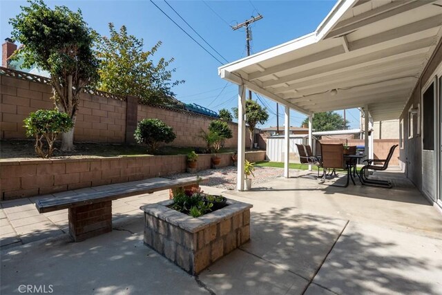 view of patio / terrace featuring an outbuilding, outdoor dining area, a fenced backyard, and a storage shed