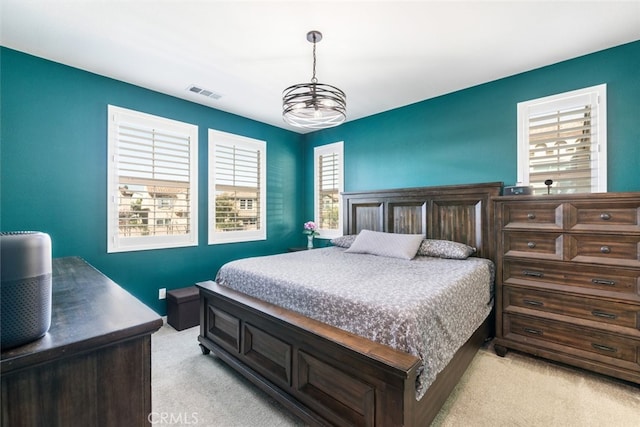 bedroom with light carpet, visible vents, and an inviting chandelier