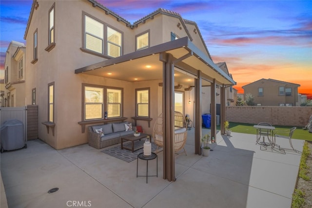 patio terrace at dusk with fence and an outdoor living space