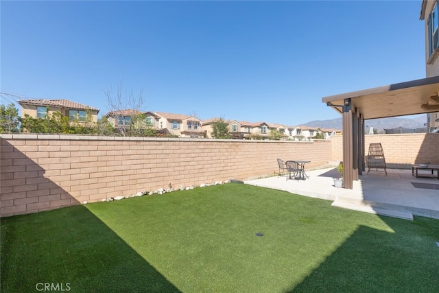 view of yard featuring a patio area, a fenced backyard, and a residential view