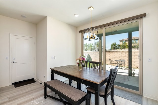 dining area with light wood finished floors, an inviting chandelier, and baseboards