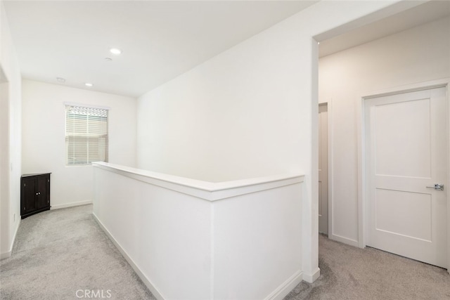 hall featuring light carpet, recessed lighting, baseboards, and an upstairs landing