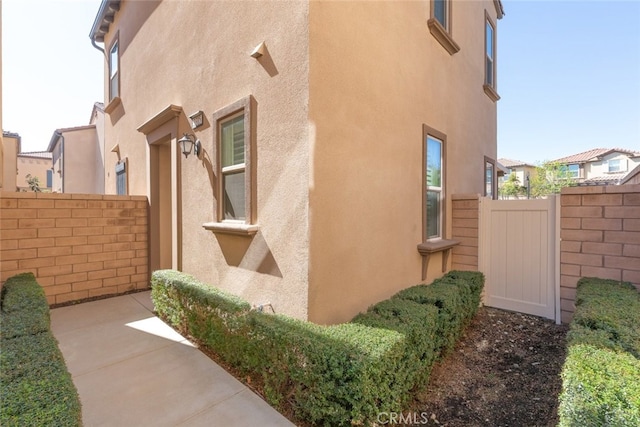 view of side of property with fence and stucco siding