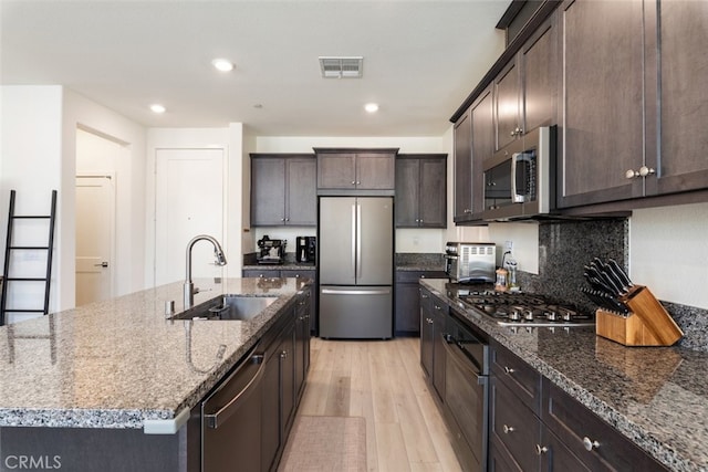 kitchen featuring light wood-style flooring, dark brown cabinetry, a sink, visible vents, and appliances with stainless steel finishes