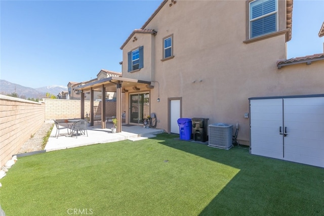 back of property with a patio, stucco siding, central AC, a mountain view, and a fenced backyard