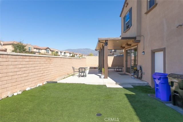 view of yard with a patio area, a fenced backyard, and a mountain view