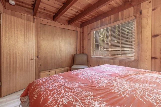 bedroom with a closet, wood ceiling, beam ceiling, and wooden walls