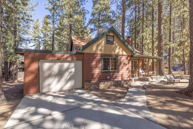 view of home's exterior featuring an attached garage, driveway, a chimney, and a porch