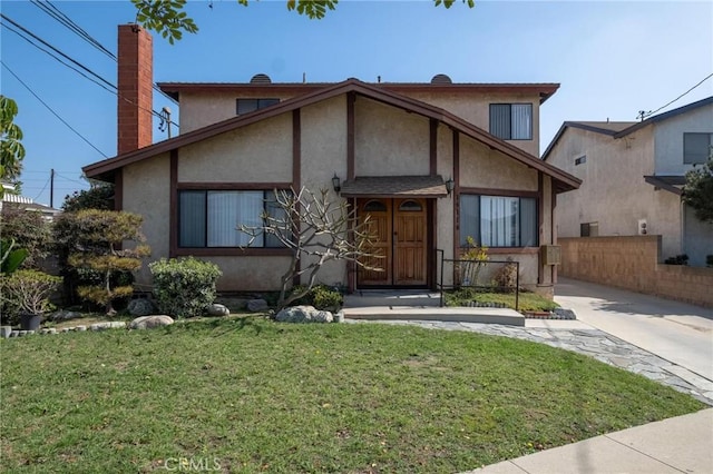 view of front of property with a front lawn, fence, and stucco siding