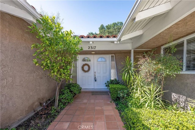 view of exterior entry featuring a tiled roof and stucco siding