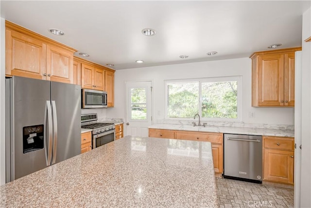 kitchen featuring light stone countertops, stainless steel appliances, a sink, and recessed lighting