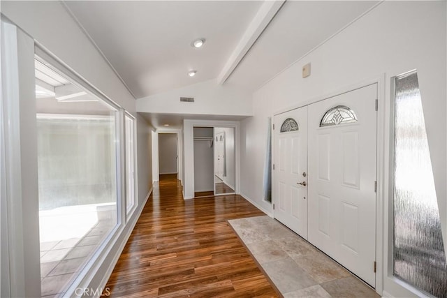 entrance foyer featuring visible vents, vaulted ceiling with beams, baseboards, and wood finished floors