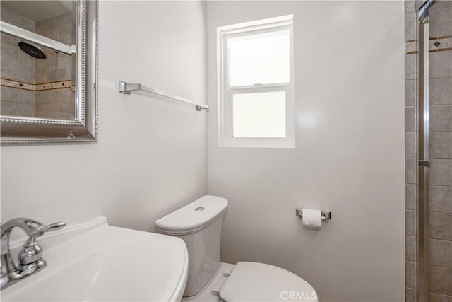 bathroom featuring a sink, a tile shower, and toilet