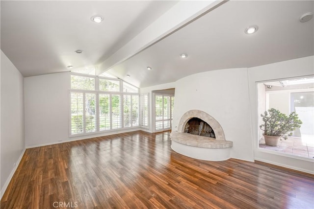 unfurnished living room with baseboards, a fireplace with raised hearth, wood finished floors, vaulted ceiling with beams, and recessed lighting