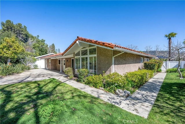 rear view of house with a yard, a gate, fence, and stucco siding