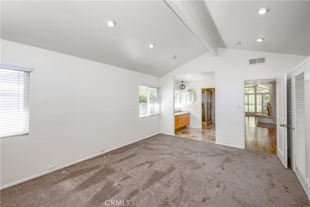 unfurnished bedroom with light carpet, multiple windows, visible vents, and vaulted ceiling with beams