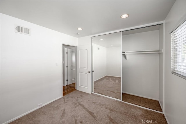 unfurnished bedroom with recessed lighting, carpet floors, visible vents, baseboards, and a closet