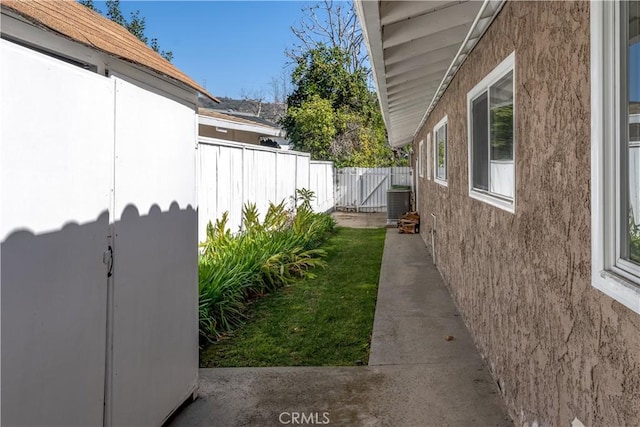 view of side of property with central AC and fence