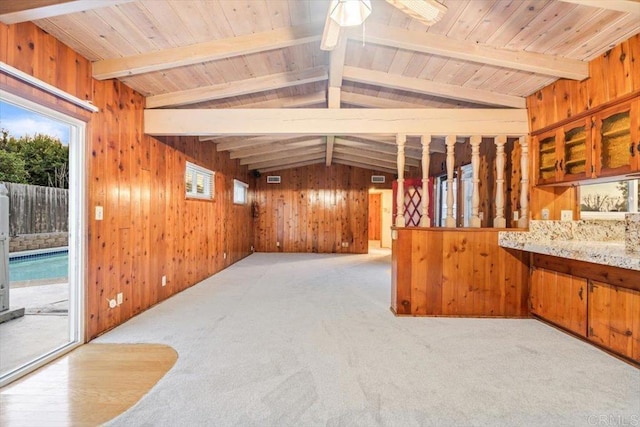 interior space with wooden walls, vaulted ceiling with beams, and carpet