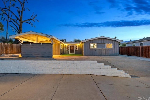 ranch-style house featuring board and batten siding and fence
