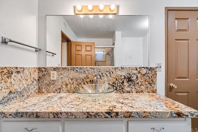 bathroom with vanity, visible vents, backsplash, and a stall shower