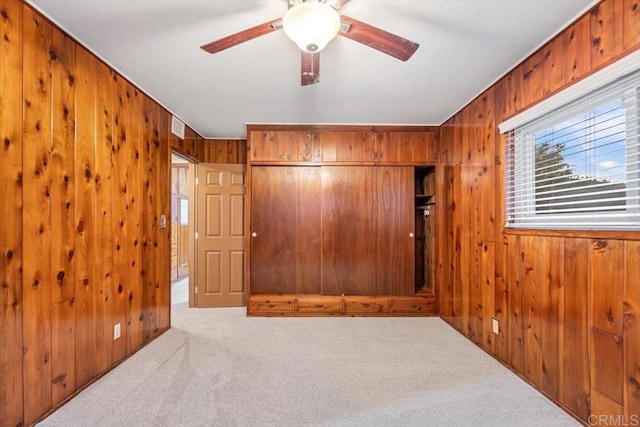 unfurnished room featuring wood walls, visible vents, a ceiling fan, and carpet floors