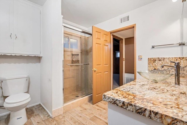full bath with visible vents, toilet, a shower stall, and wood finished floors