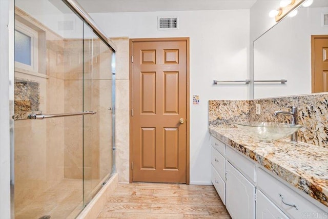 full bath featuring a shower stall, wood finished floors, backsplash, and visible vents