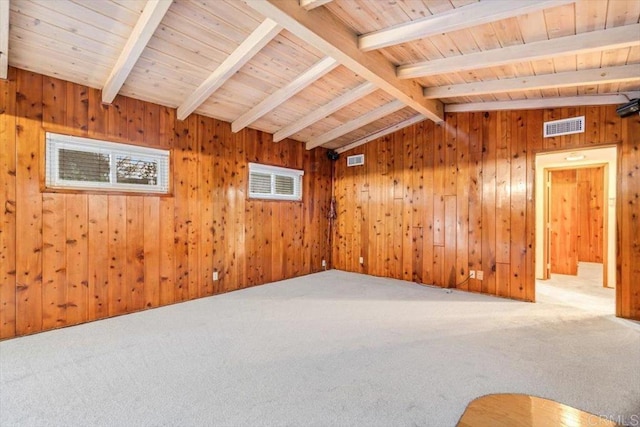 unfurnished room with wooden walls, visible vents, carpet flooring, and lofted ceiling with beams