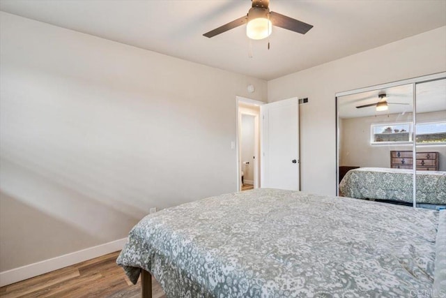 bedroom with a closet, wood finished floors, a ceiling fan, and baseboards