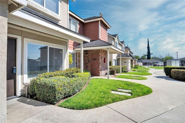 exterior space with a yard, brick siding, and a residential view