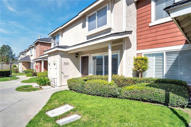 doorway to property featuring a residential view, a lawn, and stucco siding