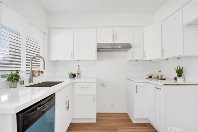 kitchen featuring light wood-style floors, dishwashing machine, under cabinet range hood, white cabinetry, and a sink