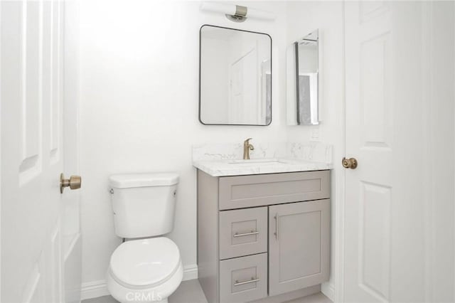 bathroom featuring toilet, vanity, and baseboards