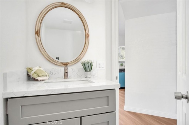 bathroom with wood finished floors, vanity, and baseboards