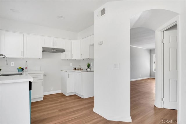 kitchen featuring light wood-style flooring, visible vents, white cabinets, and a sink