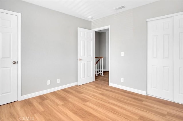 unfurnished bedroom with light wood finished floors, a closet, visible vents, and baseboards