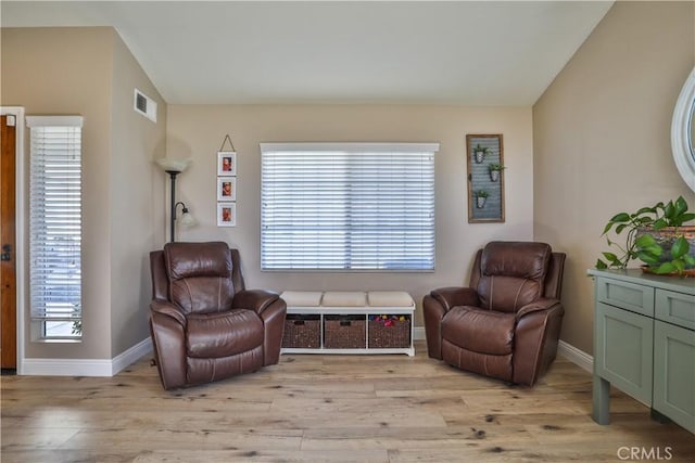 sitting room with light wood-style floors, lofted ceiling, visible vents, and baseboards