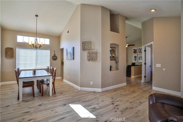 dining room featuring high vaulted ceiling, light wood-style flooring, and baseboards