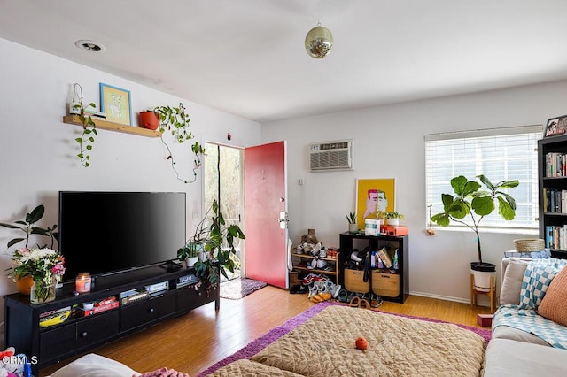 living area with a wall mounted AC and wood finished floors