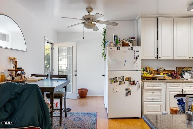 kitchen with light wood finished floors, ceiling fan, white cabinets, and freestanding refrigerator